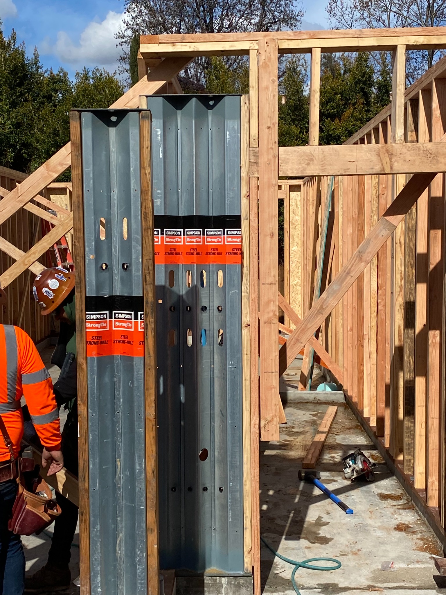 Timber wall framing with tall steel components and diagonal timber bracing at a construction site.